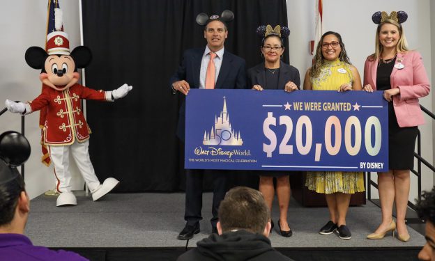 Cast members and Mickey Mouse granting a check