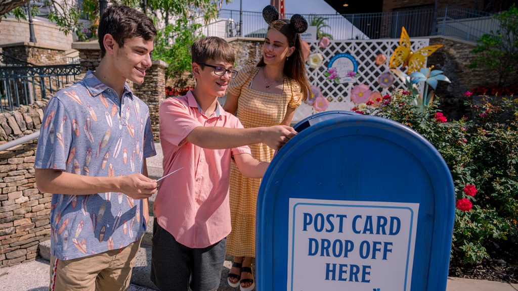 Family mailing a postcard from the “Love Grows Here” table at Disney Springs