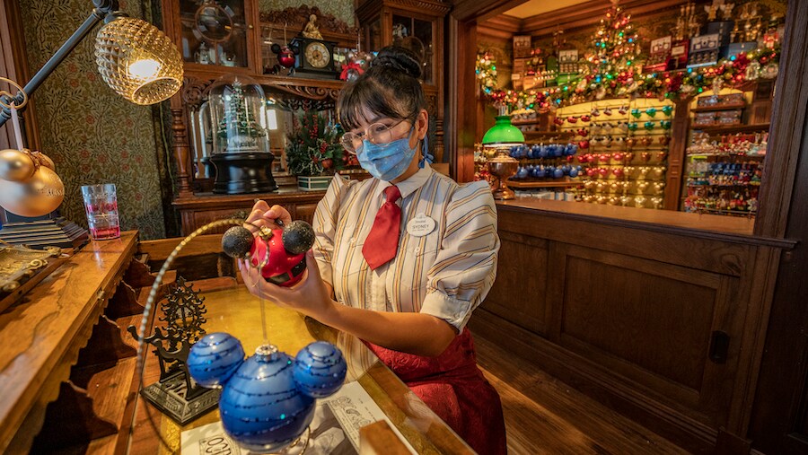 A Disneyland Resort Cast Member personalizes a holiday ornament at Plaza Point