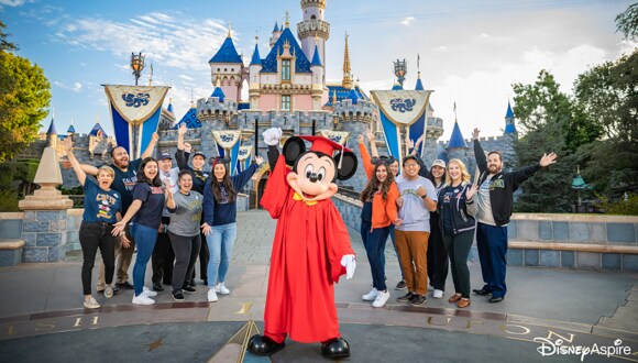 Mickey with cast members in front of Disneyland Castle