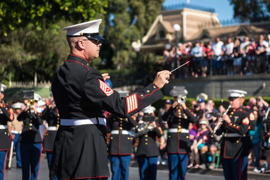 Military band conductor performing in front of crowd at Disneyland park