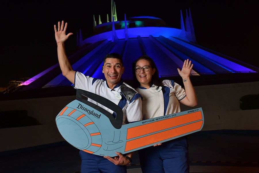 Cast members pose in front of Space Mountain with a rocket photo prop