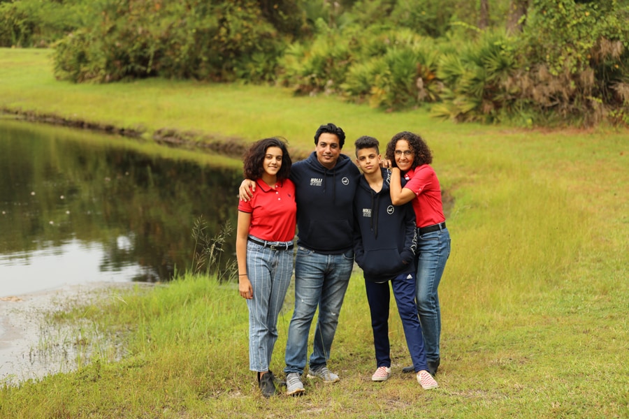 Noha Aly, her two children, and her husband pose in front of a pond.