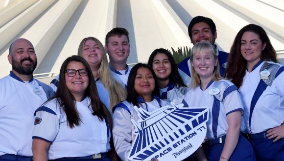 Smiling Space Mountain cast members gather in front of the attraction