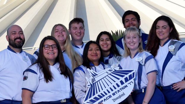 Smiling Space Mountain cast members gather in front of the attraction