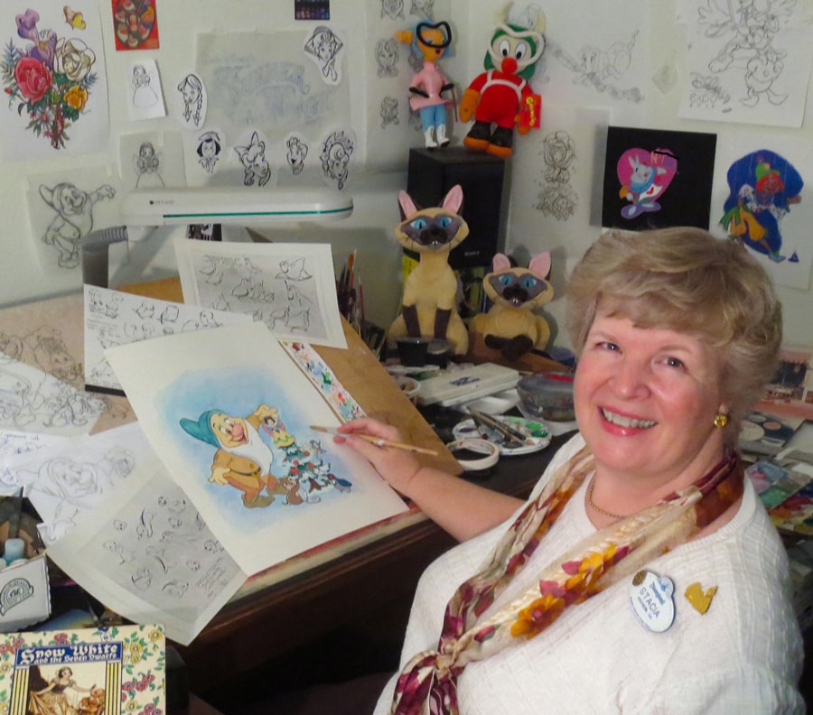 Stacia Martin at her animation desk surrounded by sketch drawings of various Disney characters
