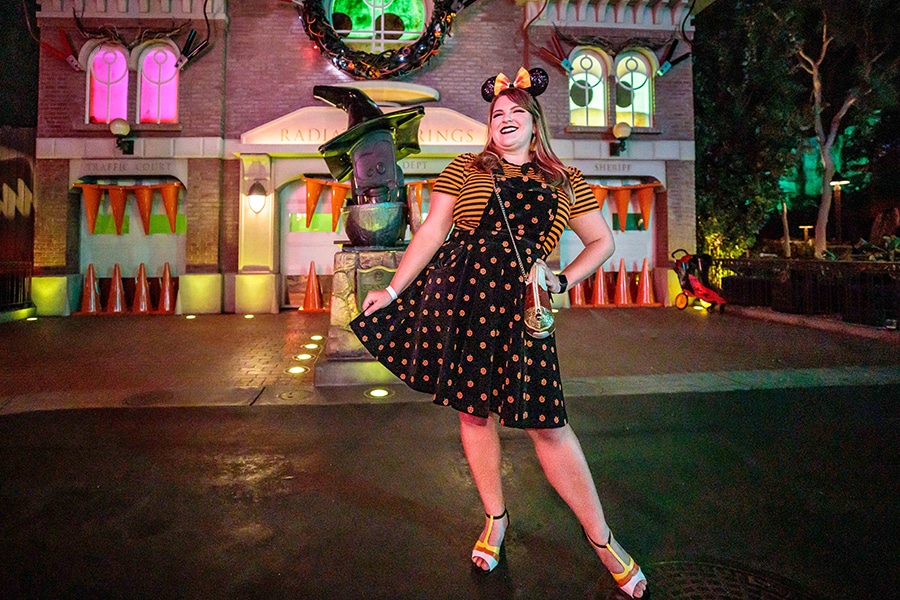 A female cast member in a festive Halloween outfit poses in Radiator Springs