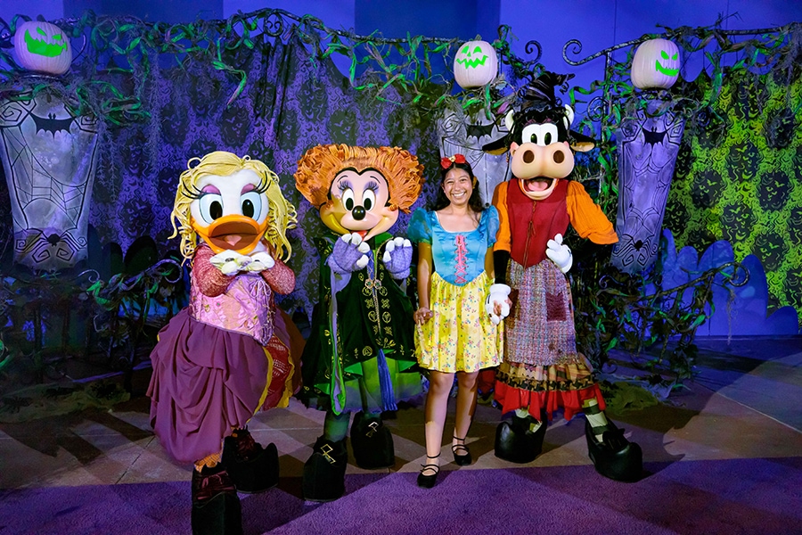 A cast member in a Snow White costume poses with Daisy, Minnie and Clarabelle dressed as the Sanderson Sisters