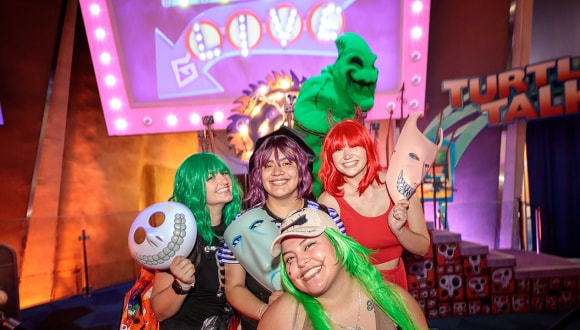 Cast members in festive Halloween outfits pose in front of Oogie Boogie