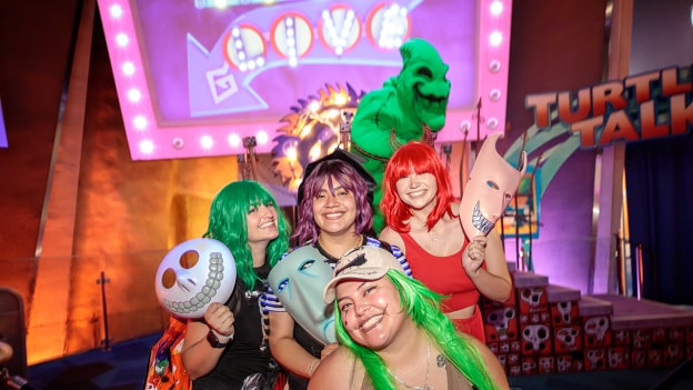 Cast members in festive Halloween outfits pose in front of Oogie Boogie