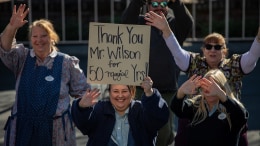 Cast members holding sign that reads "Thank you Mr. Wilson for 50 Magical Years"
