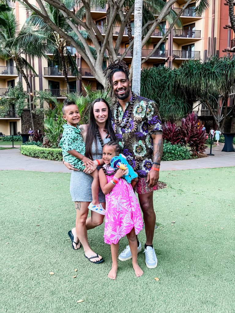 Ashley and her family on the lawn of Aulani Resort dressed in beautiful Hawaiian floral shirts and dresses