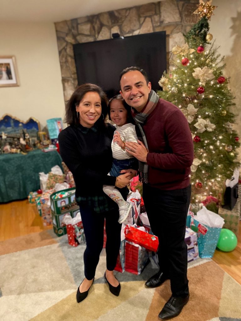 Cast Member Alejandro poses with his wife and daughter in front of their Christmas Tree.