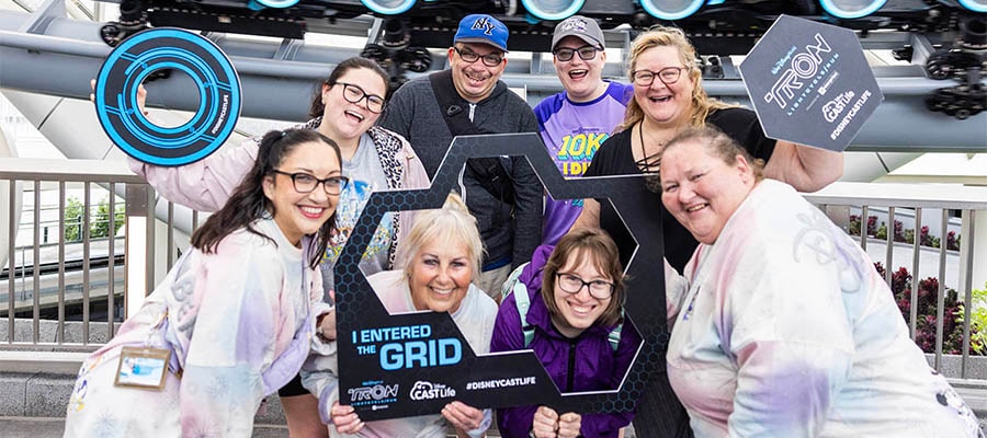 Group of cast members pose with TRON frame that says 'I entered the grid'