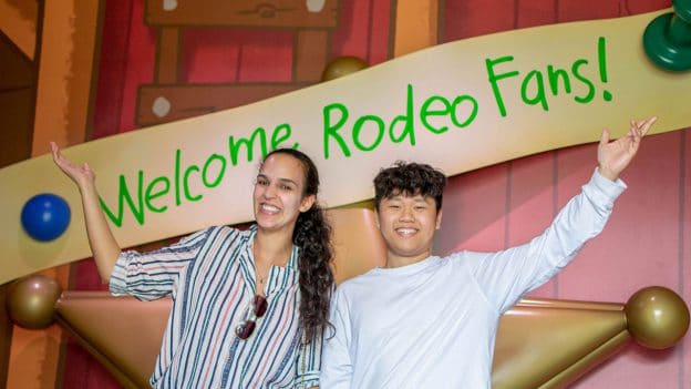 Students pose in front of Roundup Rodeo BBQ welcome sign.