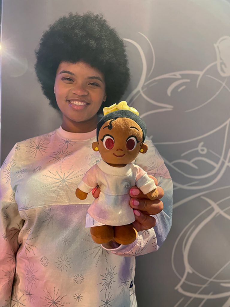 Claire smiles holding up her Princess Tiana Nuimo
