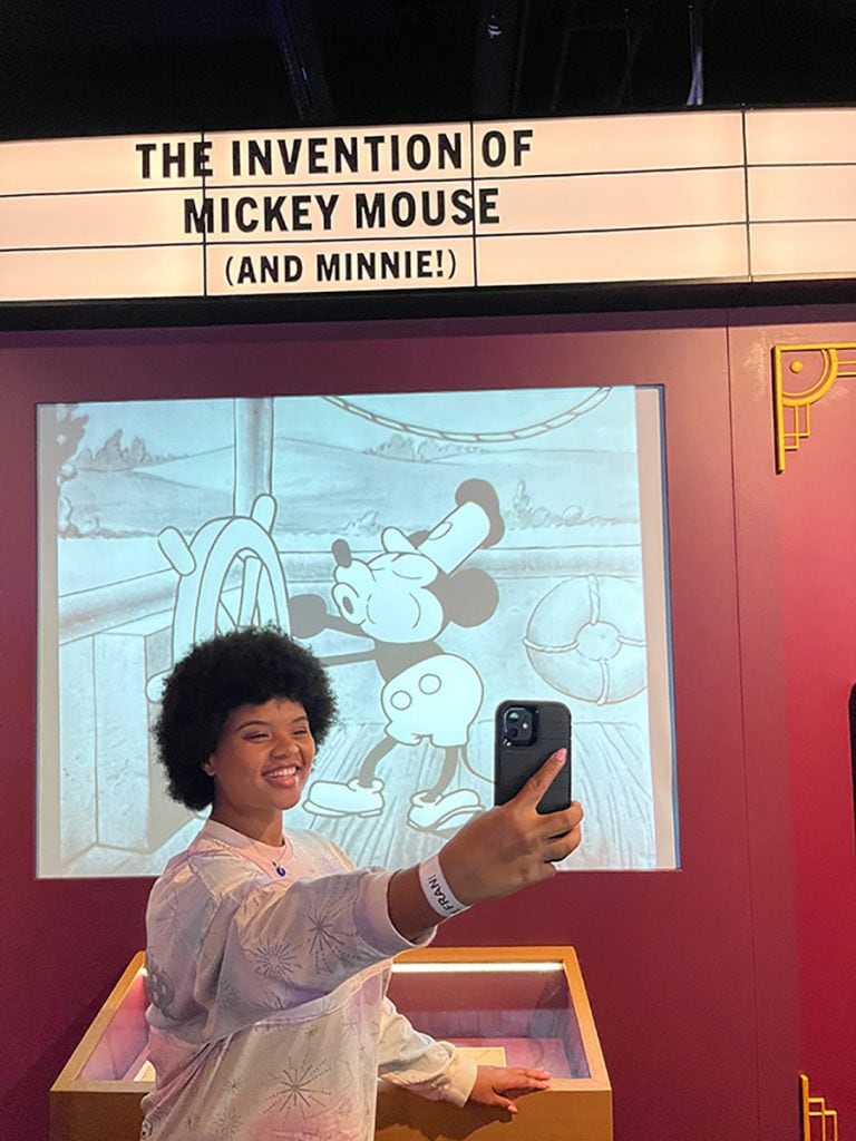 Claire snaps a selfie as "Steamboat Willie" plays in the background