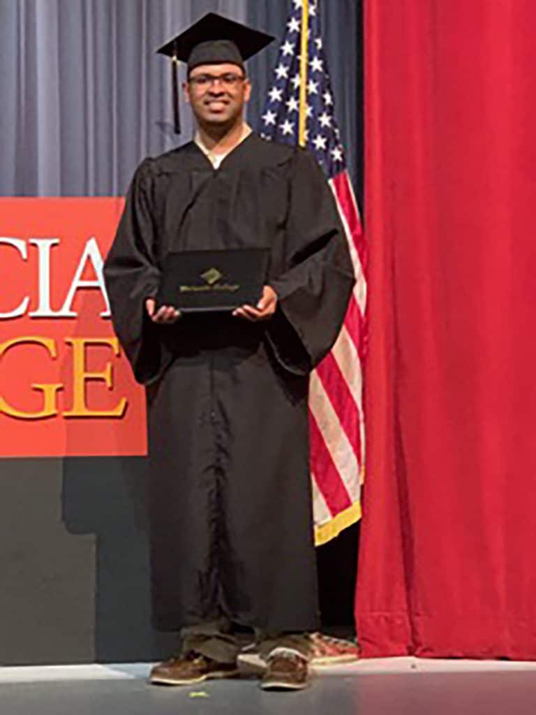 Guillermo smiles in a cap and gown at his graduation ceremony.
