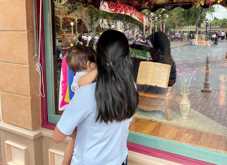Allie holds her son looking at the Main Street window display