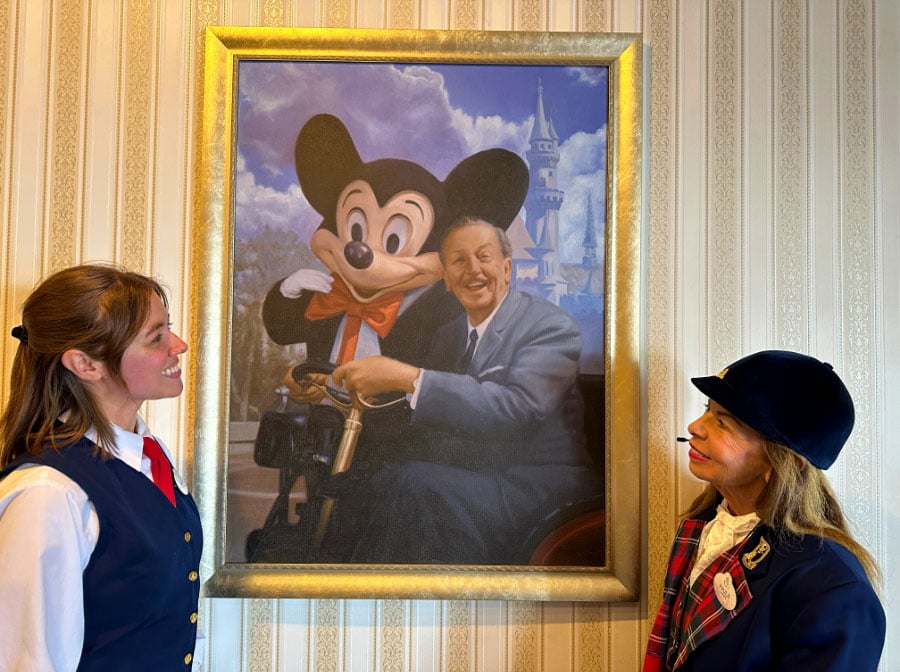 Sam and Paula look at a portrait of Walt Disney and Mickey Mouse