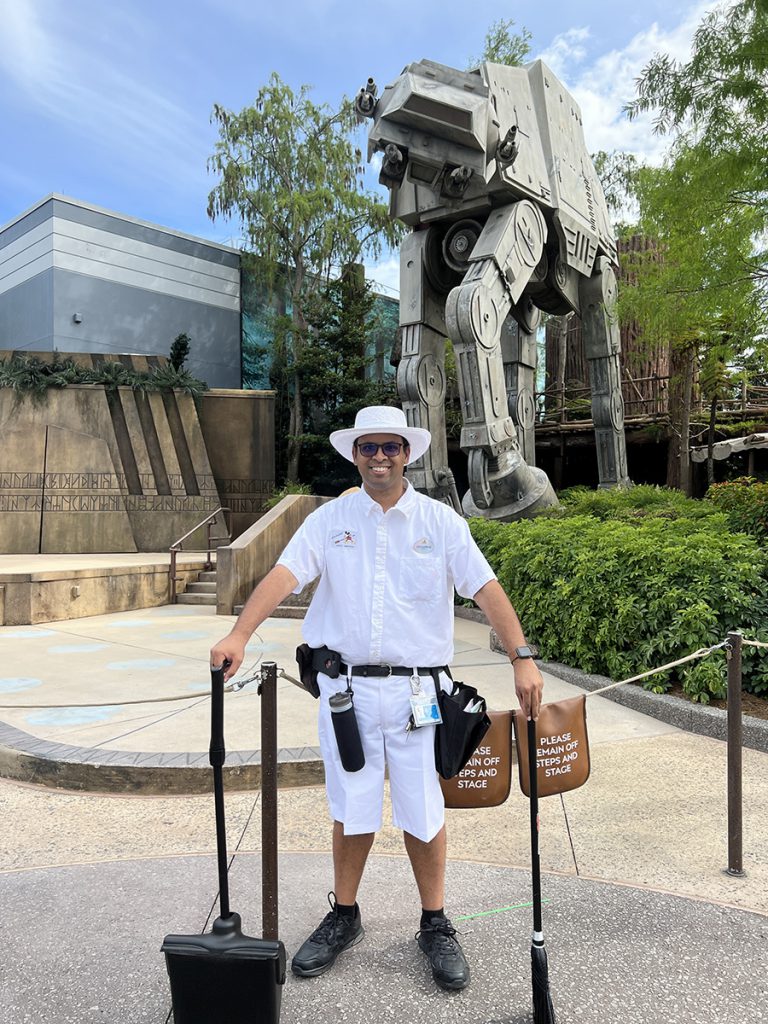 Guillermo smiles in his Custodial costume in front of Star Tours – The Adventures Continue at Disney's Hollywood Studios.