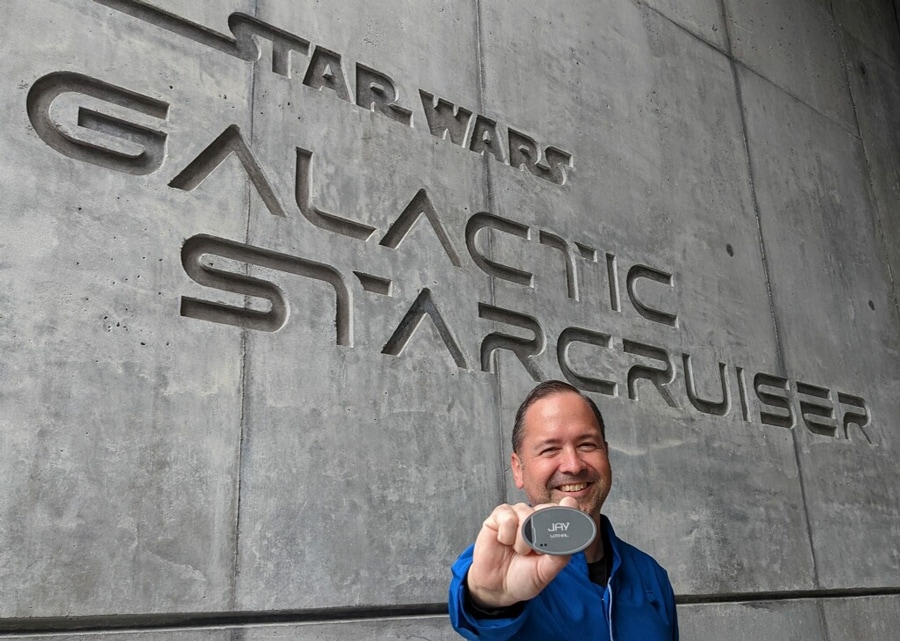 Cast Member Jay holding his name tag standing in front of Star Wars galactic star cruiser sign