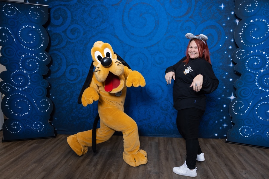 Cast member with Pluto posing with hands in air mimic Pluto holding up his paws