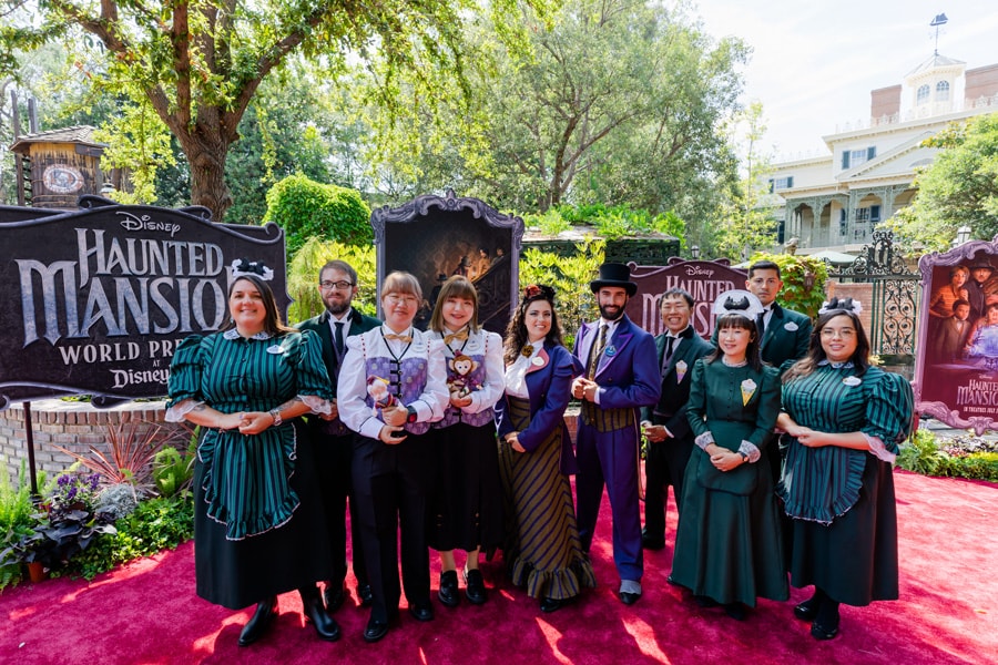 A global group of Haunted Mansion cast standing on the red carpet in New Orleans Square
