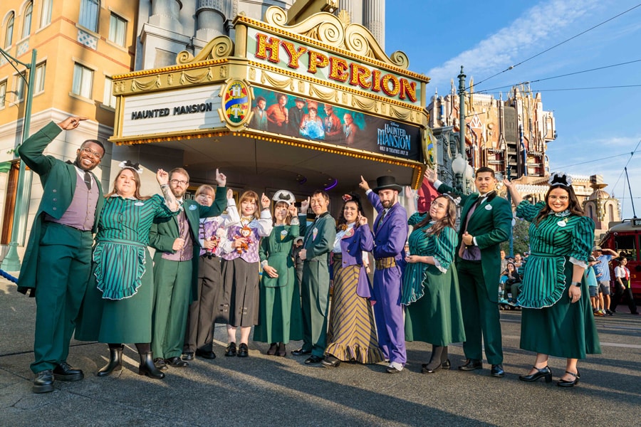 A global group of Haunted Mansion cast in front of the Hyperion Theater marquee