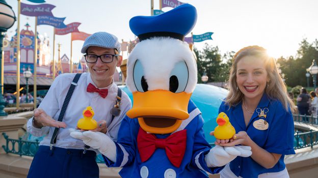 Disneyland Paris Ambassadors Quentin and Carmen smile with rubber ducks and Donald Duck outside "it's a small world."