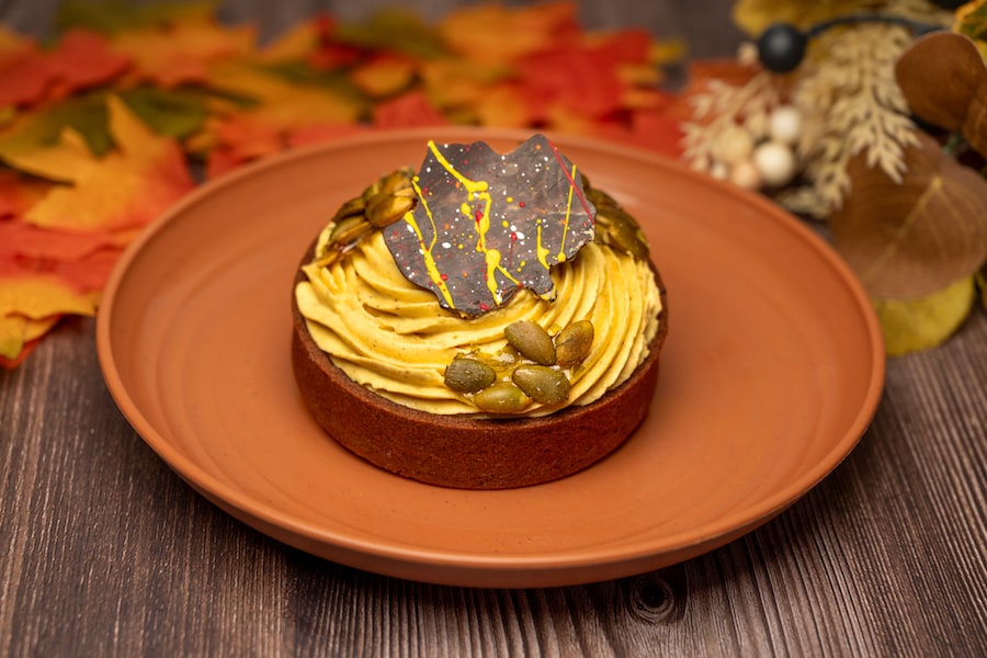Pumpkin-Hazelnut Tart: Chocolate tart shell filled with hazelnut ganache and spiced pumpkin cheesecake garnished with chocolate décor and candied pumpkin seeds (New) - Centertown Market in Disney’s Caribbean Beach Resort (Available Sept. 1 through Nov. 30; mobile order available)
