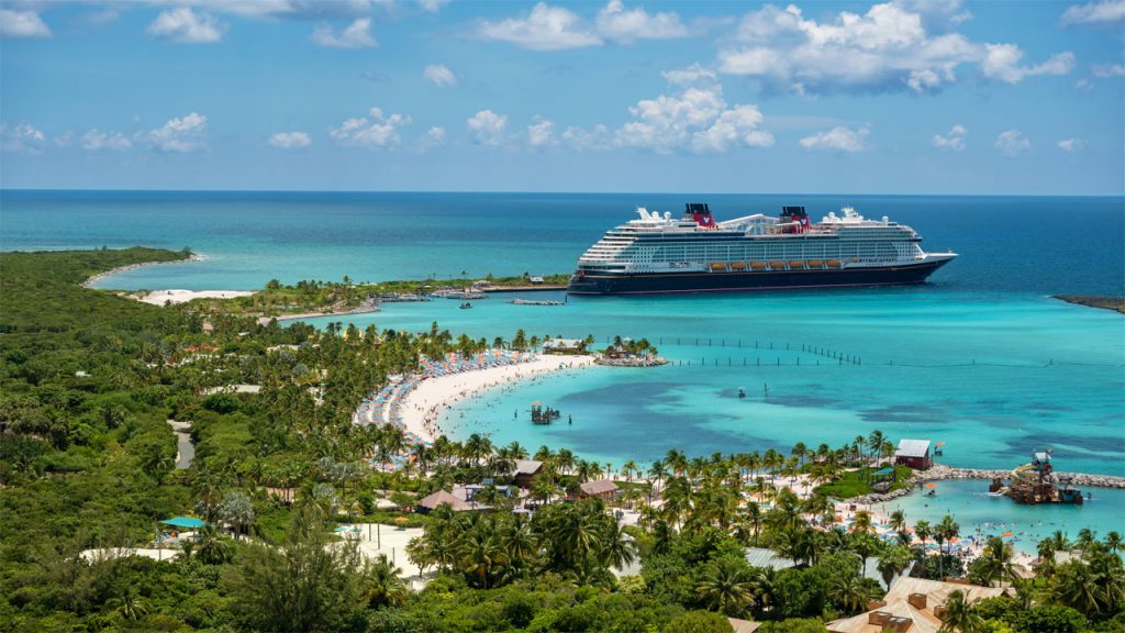 A disney cruise ship docked at a beach in the caribbean.