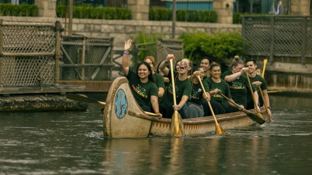Rivers of FAMerica team members smile as they paddle a canoe along the Rivers of America