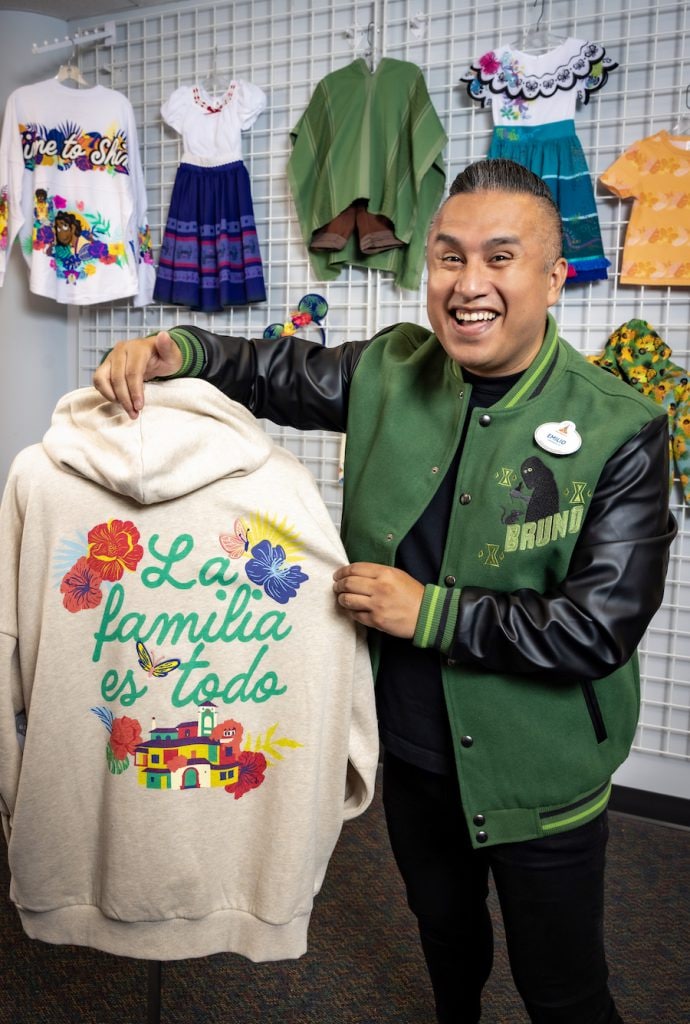 Emilio posing with a pullover hoodie from the Encanto La Familia Madrigal collection