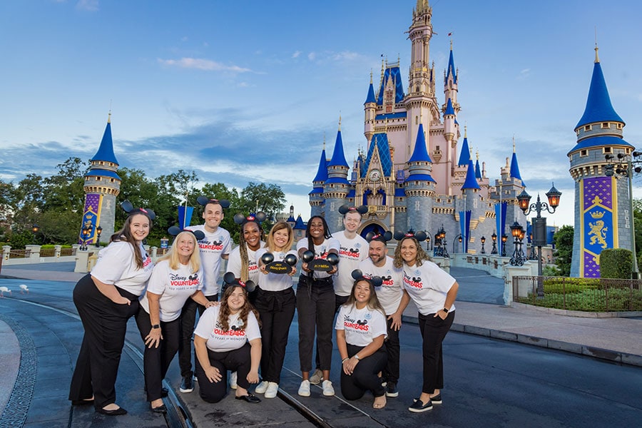Image of Disney World cast member volunteers posing in front of Cinderella Castle.