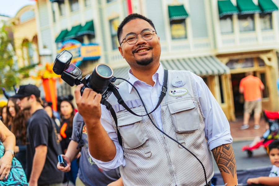 A PhotoPass photographer smiles with his camera at ready on Main Street, U.S.A.