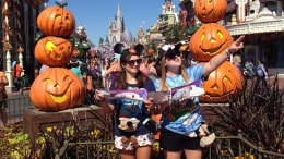 Photo of Courtney and Heather in front of Magic Kingdom castle and pumpkins looking at map and acting like tourists