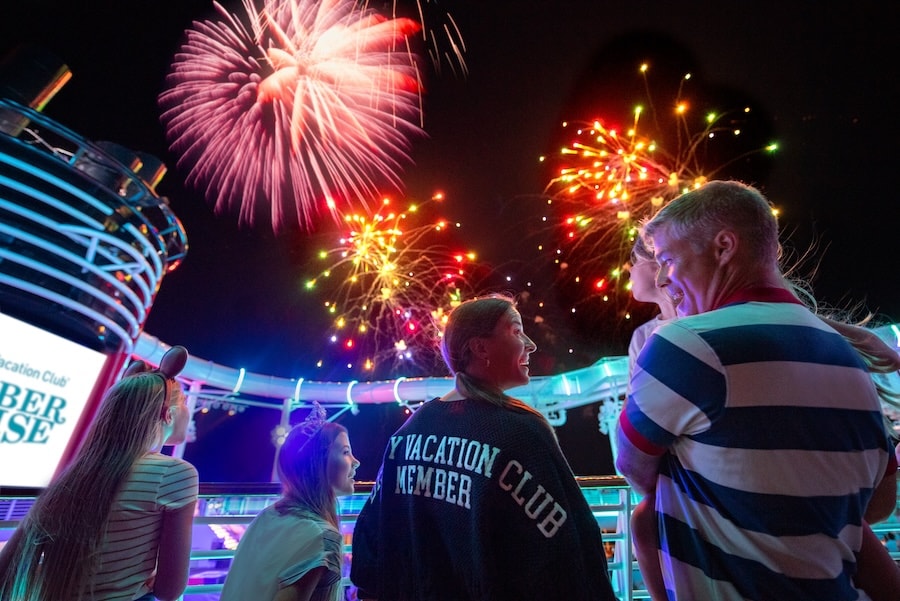 Family watching fireworks at night while on a Disney cruise