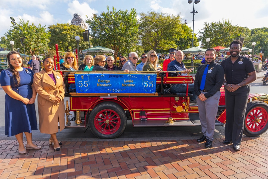 George and Louie aboard the Main Street fire engine with their families, flanked by Disney Ambassadors