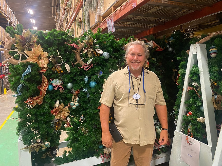 Ed smiles in front of a cart of holiday decorations for Disney's Yacht and Beach Club Resorts. 