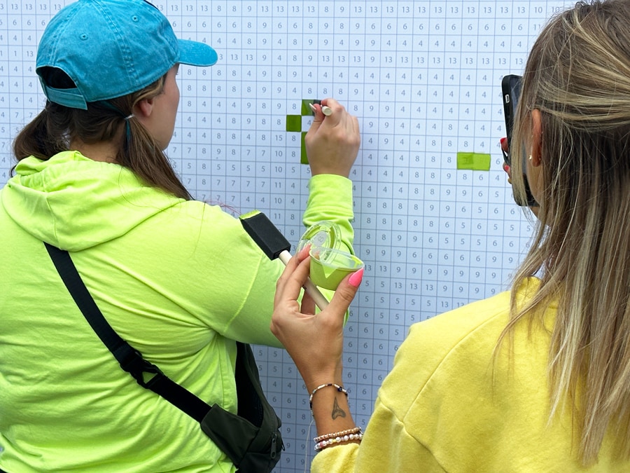 Image of guest applying green paint at the Expression Section Paint by Numbers mural during EPCOT Festival of the Arts 2024