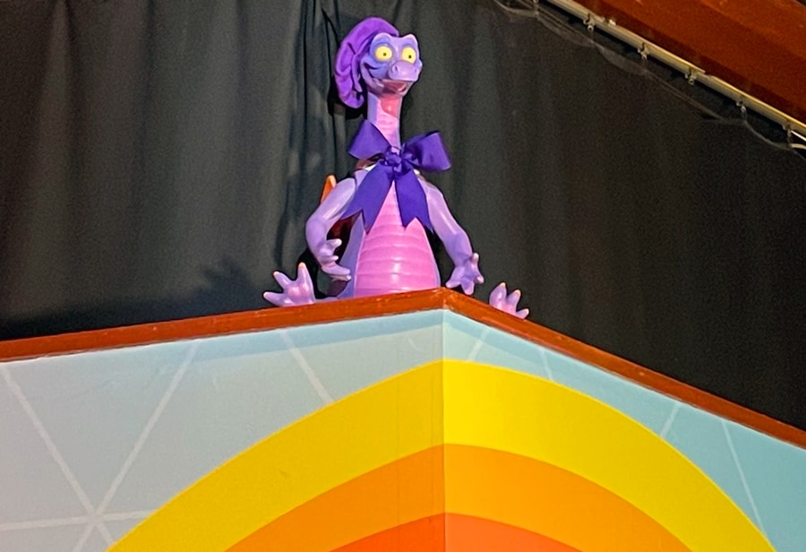 Image of Figment wearing a purple bow tie and purple beret hat inside Figment's Inspiration Station at EPCOT International Festival of the Arts
