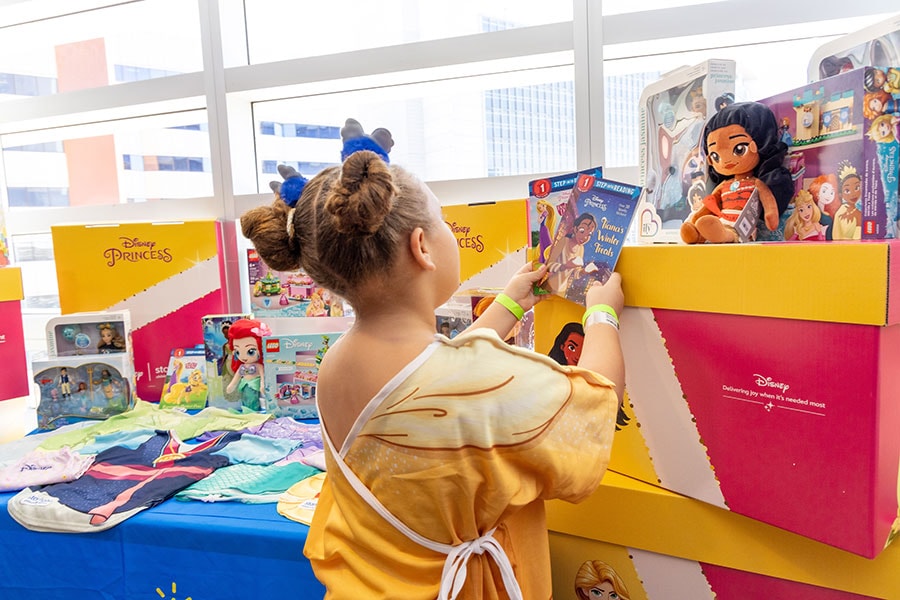 Child holding two Disney books in a Belle-inspired hospital gown