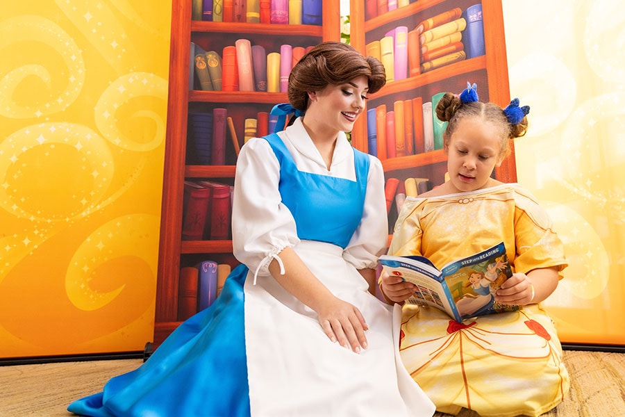 Girl reading a Disney books to Belle in a Belle-inspired hospital gown
