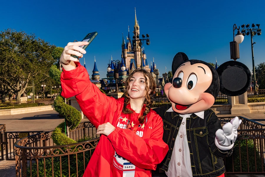 Member of Tragedy Assistance Program for Survivors taking a selfie with Mickey Mouse at Magic Kingdom Park