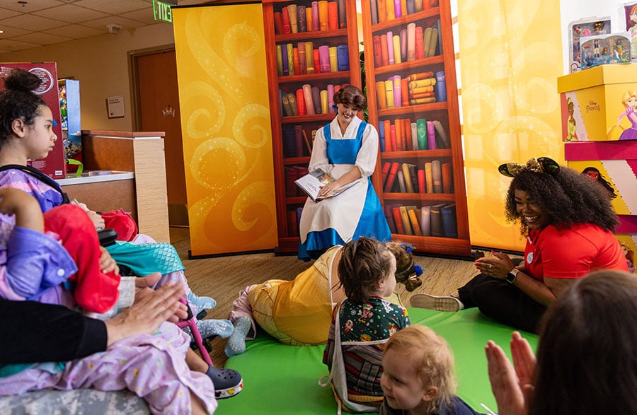 Belle reading a book to children's hospital patients during a princess party