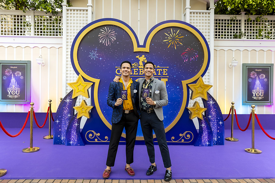 Randolf and Rodolf pose together in front of a Mickey Mouse shaped photo backdrop.  