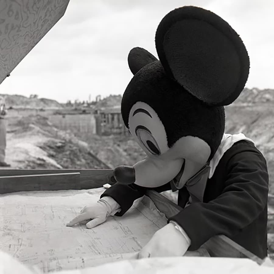 Mickey Mouse inspecting a blueprint of Magic Kingdom