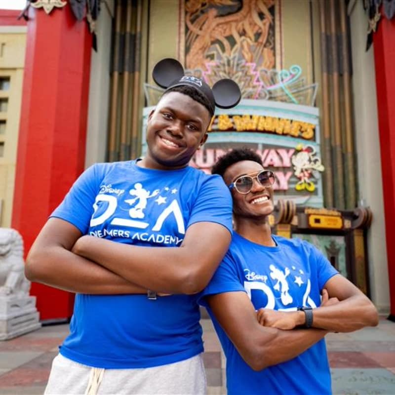 Two students posing together for a photo in front of Mickey & Minnie's Runaway Railway