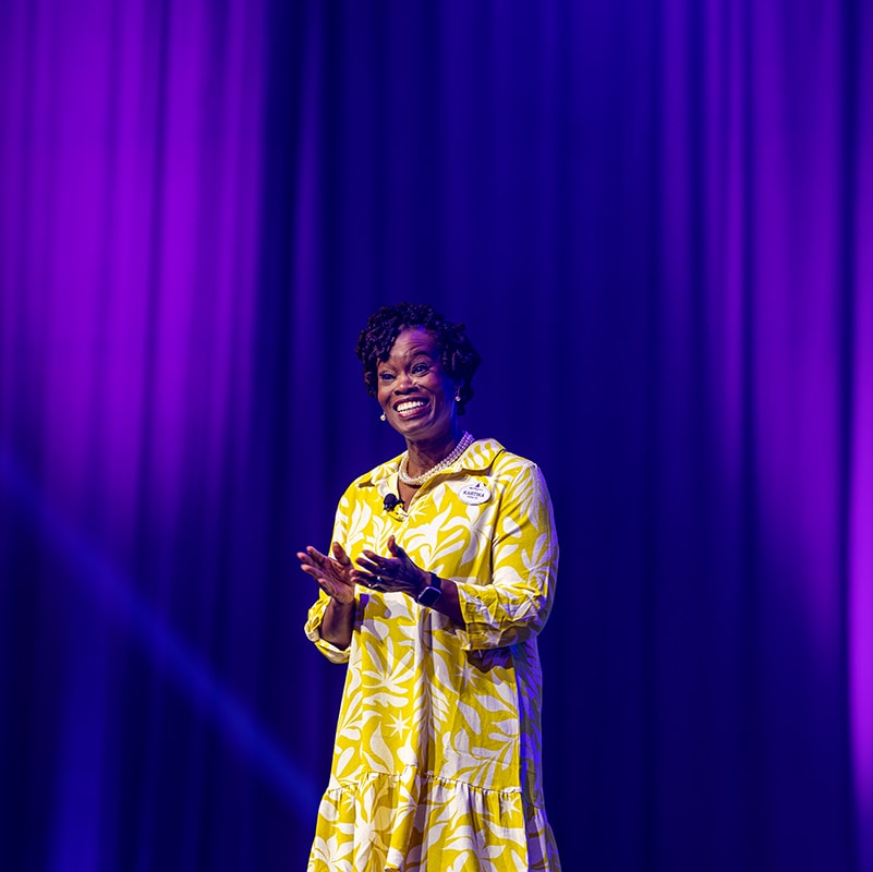 A Disney Cast Member smiling while giving a presentation on stage